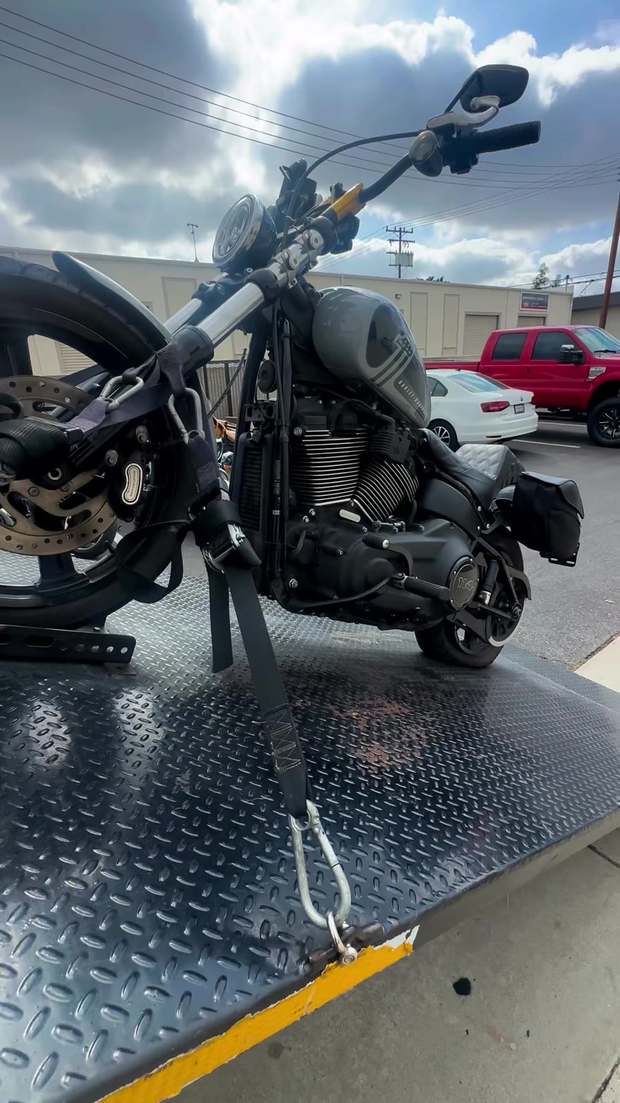 Harley Softail secured with straps on black bed