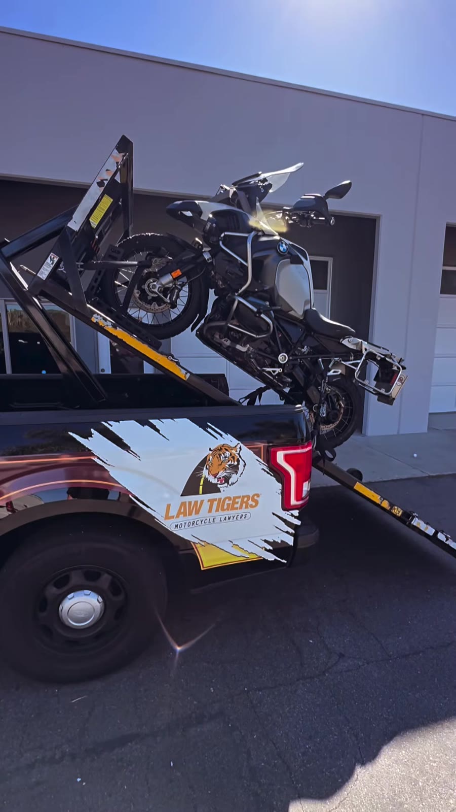 BMW adventure bike on Law Tigers black truck hydraulic lift